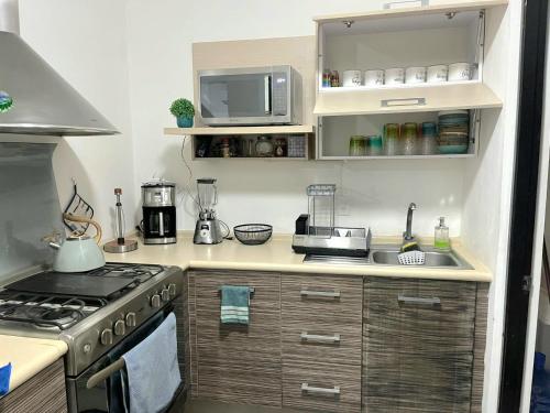 a small kitchen with a stove and a microwave at Kaan Town Houses Cancún in Cancún