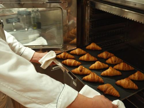 a person is putting food in an oven at Urayasu Brighton Hotel Tokyo Bay in Urayasu