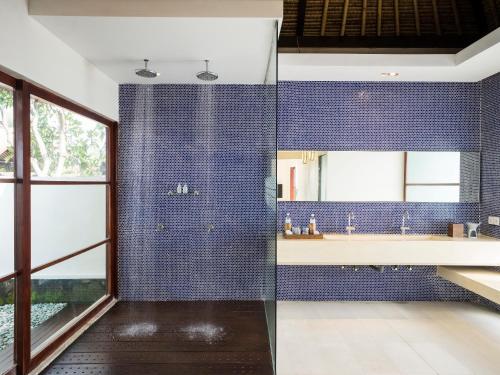 baño con paredes de azulejos azules y espejo en The Samata by LifestyleRetreats en Sanur