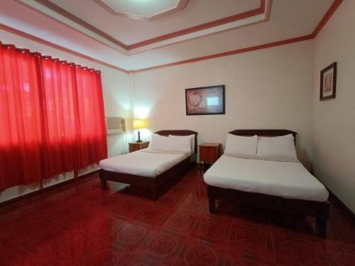 two beds in a room with red curtains at Northomes Pensione by HiveRooms in Bogo