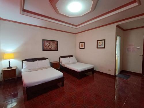 a room with two beds and a table and a lamp at Northomes Pensione by HiveRooms in Bogo