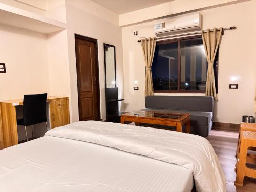 a bedroom with a bed and a chair and a window at BKC Apartment in Siliguri