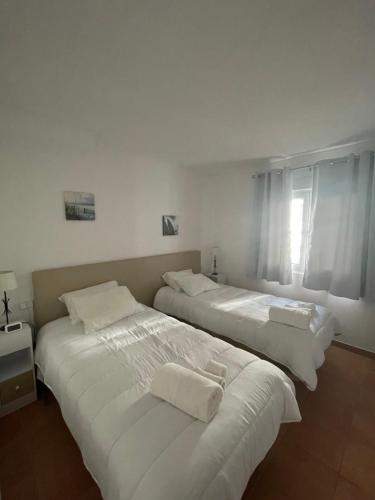 two beds in a room with white walls at OuraSea Apartment in Albufeira