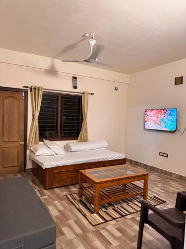 a bedroom with a large bed and a table at BKC Apartment in Siliguri