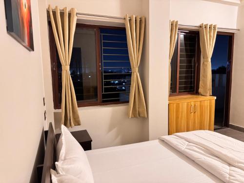 a bedroom with a bed and a window at BKC Apartment in Siliguri
