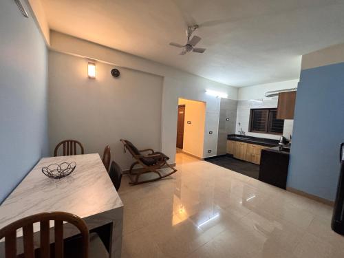 a living room with a table and a kitchen at BKC Apartment in Siliguri