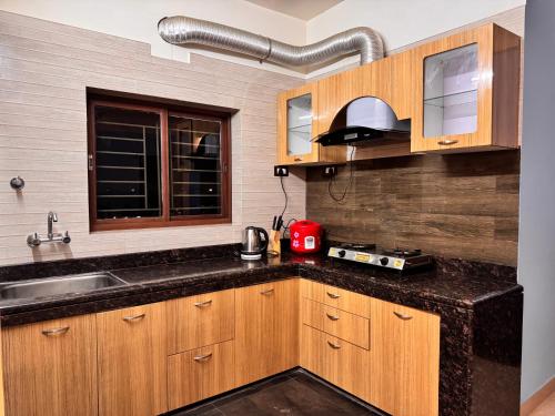 a kitchen with wooden cabinets and a sink at BKC Apartment in Siliguri