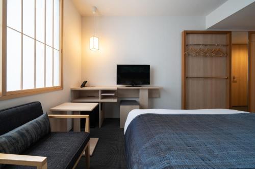 a hotel room with a bed and a couch and a tv at Hotel Vista Premio Kyoto Nagomi tei in Kyoto
