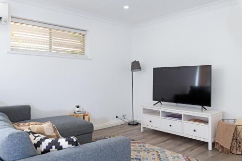 a living room with a flat screen tv on a white cabinet at Brewers Haus - Willunga - C21 SouthCoast Holidays in Willunga