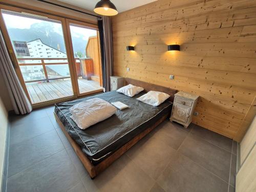 une chambre avec un lit dans un mur en bois dans l'établissement Appartement neuf lumineux, 250m pistes, balcon, animaux admis - FR-1-811-23, à Les Deux Alpes