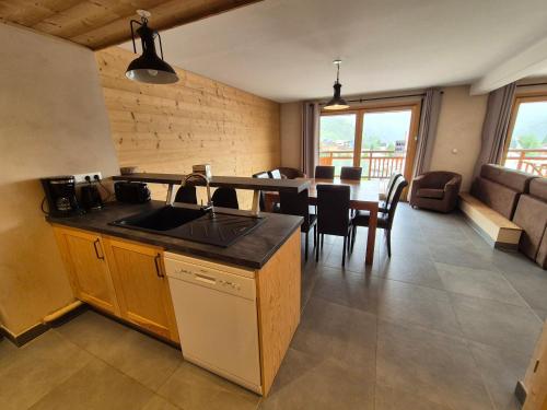 une cuisine avec un évier et une table avec des chaises dans l'établissement Appartement neuf lumineux, 250m pistes, balcon, animaux admis - FR-1-811-23, à Les Deux Alpes