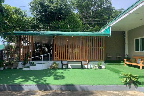 a patio with a bench and a table on the grass at Green Dale's Travellers Inn Puerto Princesa in Puerto Princesa City