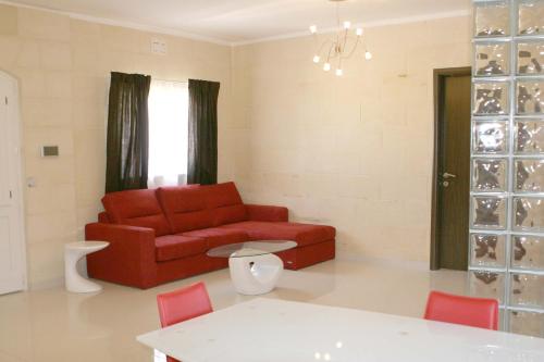 a living room with a red couch and a table at B3 Misrah Ta Cenc in Sannat