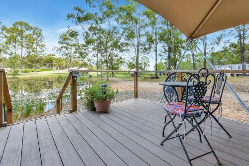 a wooden deck with a table and chairs on it at Pokolbin Glamping - Sleeps 2. Eco-Friendly Single Glamping Tents in Pokolbin