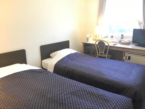 a hotel room with two beds and a desk with a computer at 衣浦グランドホテル in Takahama