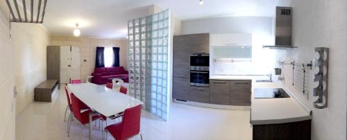 a kitchen with a table and red chairs in a room at B3 Misrah Ta Cenc in Sannat