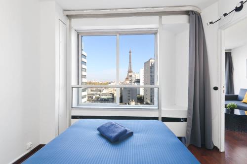 une chambre avec un lit bleu et une grande fenêtre dans l'établissement Appartement Quartier Tour Eiffel 7 Free Netflix, à Paris