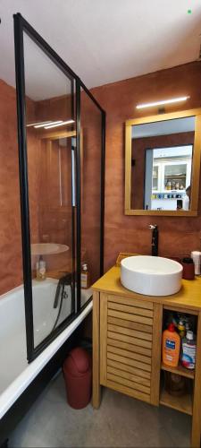 une salle de bain avec un lavabo, une baignoire et un miroir dans l'établissement Appartement avec piscines, à Canet