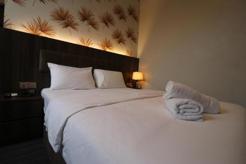 a bedroom with a large white bed with towels on it at Casa Colney Hotel Ipoh in Ipoh