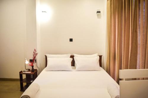 a bedroom with a bed with white sheets and pillows at Kings Kandy rooftop in Kandy