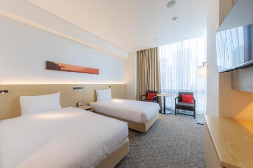 a hotel room with two beds and a table at JR Kyushu Hotel Blossom Shinjuku in Tokyo