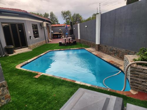 a swimming pool in a yard with green grass at Francos guest lodge accommodation in Vanderbijlpark