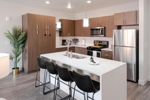 una cocina con una gran isla blanca con sillas negras en Convention Ctr Luxury 1BR Pool Gym Hot Tub, en Salt Lake City
