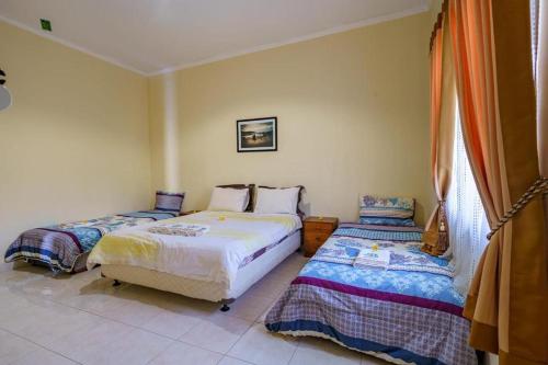 a bedroom with two beds and a window at Whiterose Guesthouse in Senggigi 