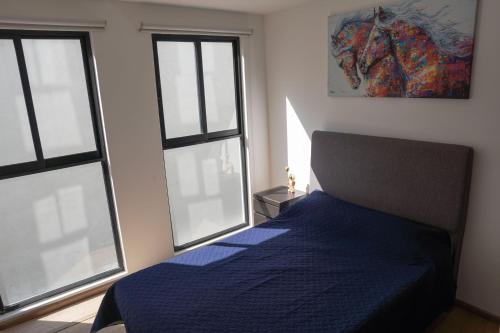 1 Schlafzimmer mit einem blauen Bett und 2 Fenstern in der Unterkunft Charming apartment near Bellas Artes in Mexiko-Stadt