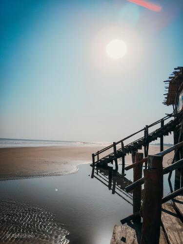 a pier on a beach next to the ocean at Sands Courtyard in Tajpur