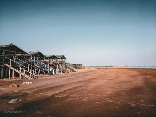 a beach with buildings and a dog laying on the sand at Sands Courtyard in Tajpur