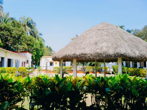 a pavilion with a straw roof in a yard at Sands Courtyard in Tajpur