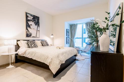 a bedroom with a bed and a vase with flowers on it at Fabulous 1BR in Dubai Marina near Beach With Sea Views in Dubai