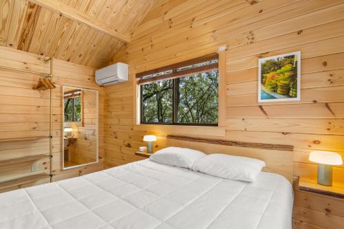 a bedroom with a white bed in a wooden cabin at Happy Travelers RV Resort in Thonotosassa