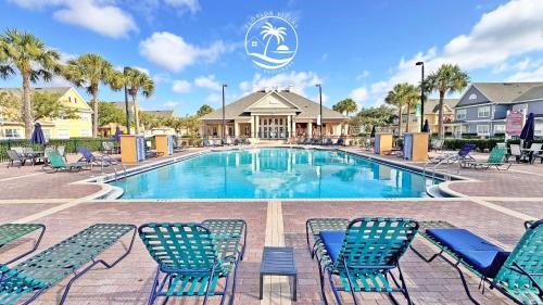 a swimming pool with blue chairs and palm trees at Villas at Seven Dwarfs - Close to Disney in Kissimmee