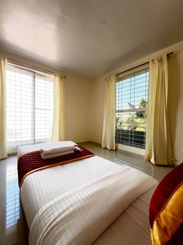 a bedroom with a large bed and two windows at Sai Grand Villa Hotel Near Bangalore Airport in Bengaluru