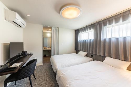 a hotel room with two beds and a desk at Wonders Hotel in Hirabari