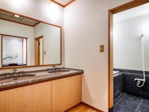 a bathroom with two sinks and a mirror at Royal Pines Hotel Chiba- Opening in Jan 2025 in Chiba