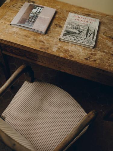 a wooden table with a chair in front of a table with books at La Maison d'Odette in La Ciotat