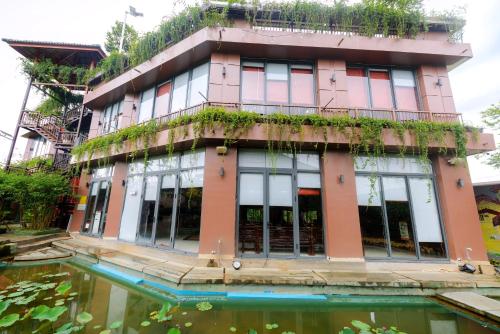 a building with a pond in front of it at Tĩnh Lạc Viên Homestay Bảo lộc in Bao Loc