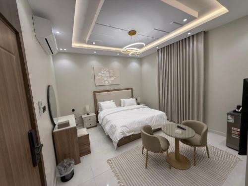 a bedroom with a bed and a table and chairs at مساكن ورد الفندقية in Al Madinah