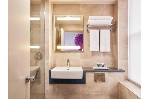 a bathroom with a sink and a mirror and towels at Exeter Rougemont Station Experience By Palette Resorts in Exeter