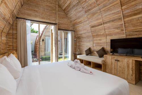 a bedroom with a large white bed and a tv at Omaneil Villa in Uluwatu