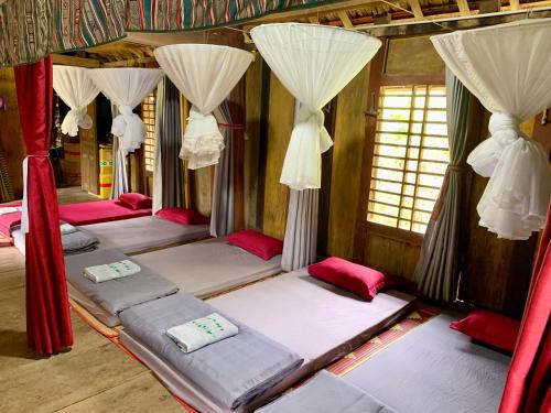 a group of four beds in a room with curtains at Dak Drinh Lodge in Dak Klong
