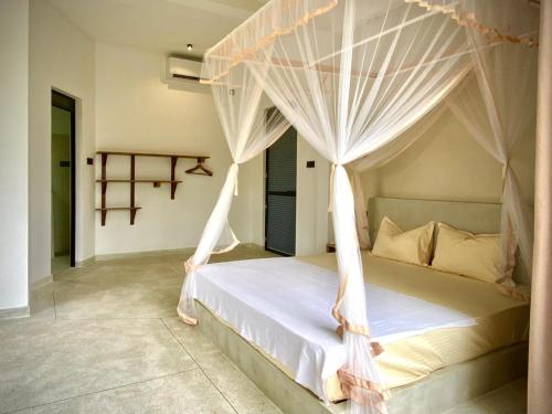 a bedroom with a canopy bed with white drapes at Lotus Surf House in Midigama