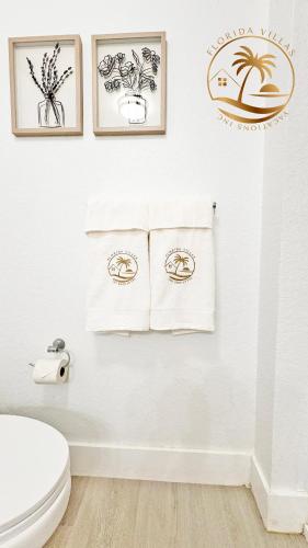 a white bathroom with three framed drawings on the wall at Villas at Seven Dwarfs - Close to Disney in Kissimmee