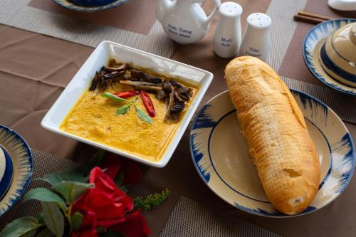 a table with a bowl of soup and a sandwich at Tĩnh Lạc Viên Homestay Bảo lộc in Bao Loc
