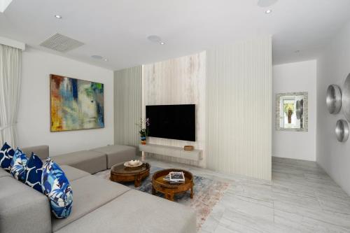 a living room with a couch and a flat screen tv at Villa Maliya in Plai Laem