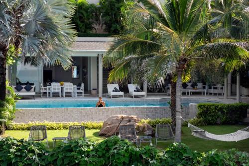 a person sitting next to a pool in a resort at Villa Maliya in Plai Laem