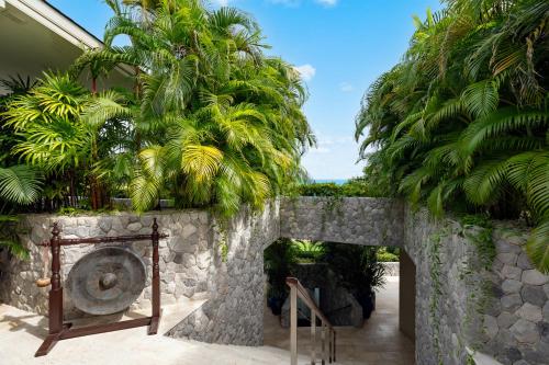 a garden with a stone wall and trees at Villa Maliya in Plai Laem